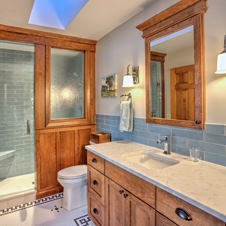 In this bathroom, we removed built-in cabinetry from an adjoining room to create an area for a spacious shower area complete with seating and ample accommodations for toiletries.
